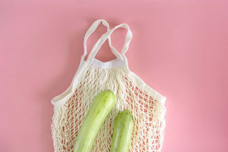Eco-friendly mesh bag with zucchinis on a pink background promoting sustainable living.